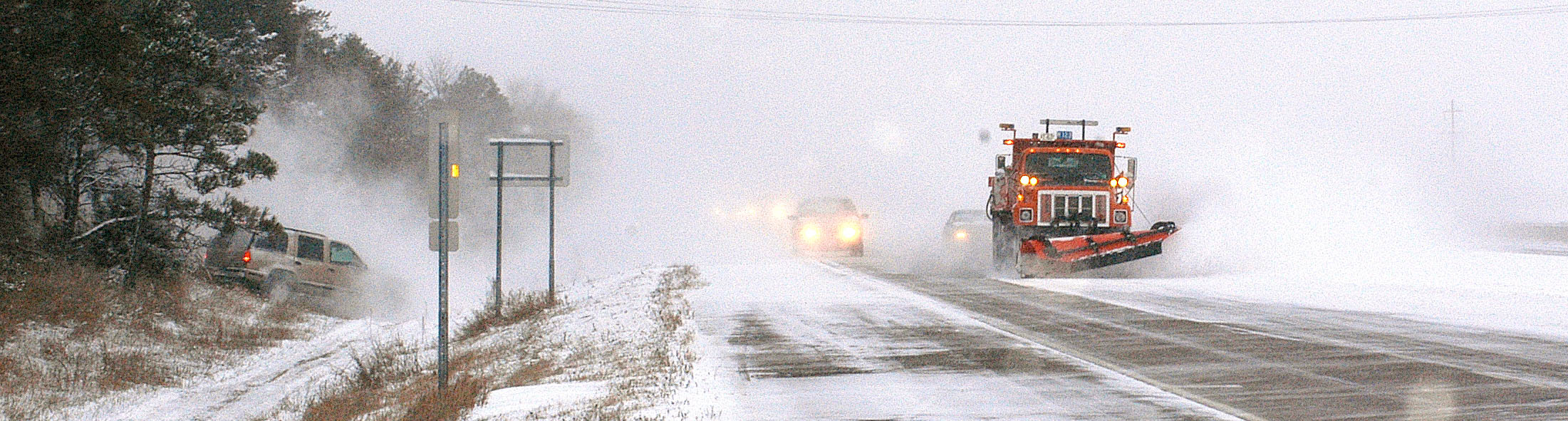 Vehicles following a plow passing an SUV in the ditch.